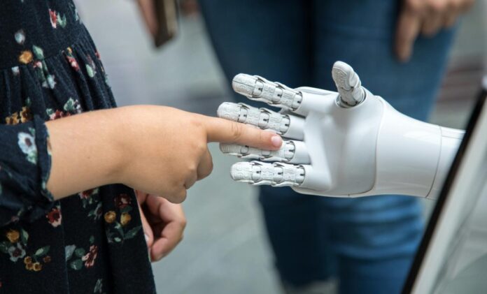 seseorang memegang tangan robot di depan cermin