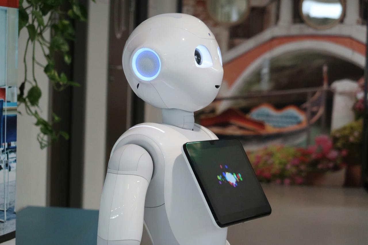 Robot putih memegang tablet di tangannya
