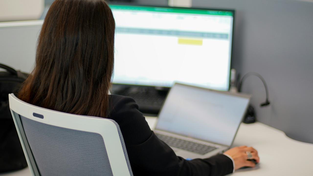 Seorang wanita duduk di depan komputer laptop