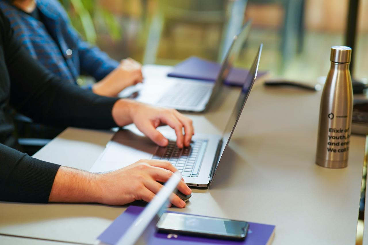 dua orang duduk di meja menggunakan laptop
